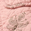 Close-up of a pink quilt with floral embroidery