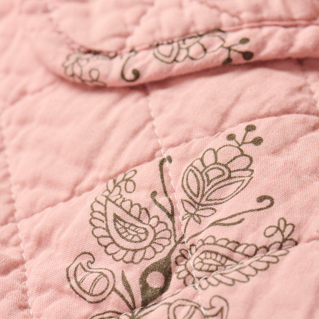 Close-up of a pink quilt with floral embroidery